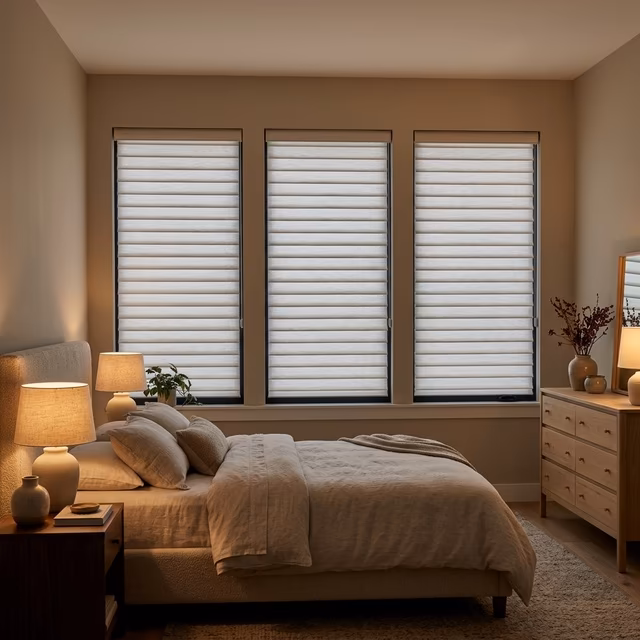 Hunter Douglas Aria fabric blinds with soft textile horizontal vanes tilted for room darkening in a modern-transitional bedroom with warm neutral tones and ambient bedside lighting, installed by La Grange Window Coverings Windsor CA 95492