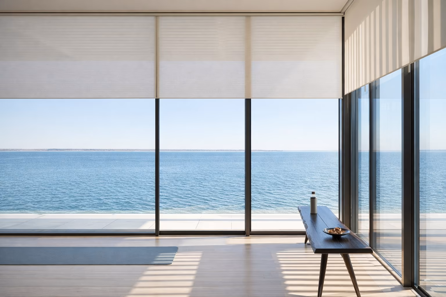 Hunter Douglas Designer Screen Shades providing solar UV filtering in a minimalist oceanfront room with floor-to-ceiling glass walls, installed by La Grange Window Coverings